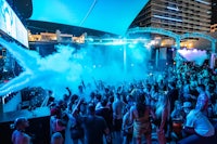 a crowd of people at a nightclub with smoke coming out of it